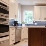 Remodeled kitchen in Herndon, VA with white cabinetry, stainless steel appliances, a wood island, and blue subway tile backsplash.