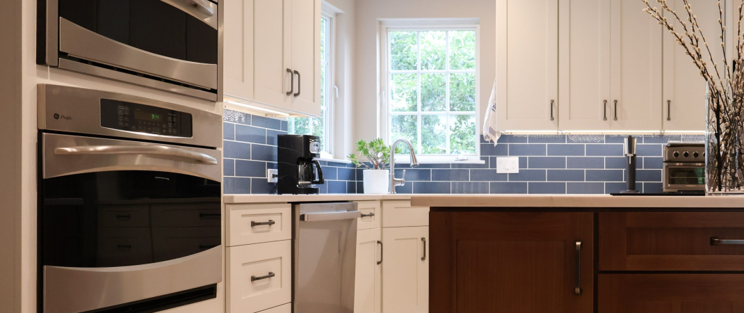 Remodeled kitchen in Herndon, VA with white cabinetry, stainless steel appliances, a wood island, and blue subway tile backsplash.